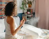 Mujer rocía almohada con spray para eliminar el olor fétido en una habitación.