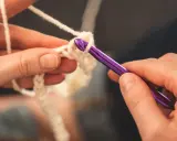 Dłonie tworzą biały wzór na szydełku ergonomicznym.
