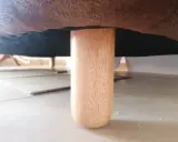 Una pata de madera de un canapé, mostrando cómo levantar un canapé del suelo para limpiarlo o moverlo.