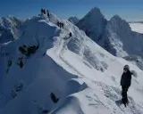 Zimowy trekking po graniach Tatr, gdzie śnieg tworzy prawdziwą koronę gór polskich. W oddali widać morze chmur.