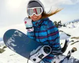 Uśmiechnięta snowboardzistka z deską, idealny dobór deski snowboardowej do wzrostu i wagi to klucz do zabawy na stoku.