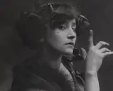 Portret kobiety z charakterystycznym pieprzykiem na policzku, przypominającej Colette. Jej dłoń uniesiona jest w tajemniczym geście.