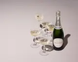 Flasche Laurent-Perrier Champagner neben gefüllten Gläsern. Ein süßer Champagner für besondere Anlässe.