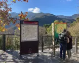 Pareja observa mapa de senderismo en los valles oriental de Montseny. El paisaje montañoso y el follaje otoñal crean un entorno pintoresco.