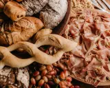 Un assortiment de pains artisanaux, de jambon cru et de raisins, parfait pour un pain sandwich italien gourmand.