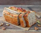 Pyszny chlebek bananowy z bakaliami, pokrojony w kromki, z widocznymi orzechami i bananem na wierzchu.