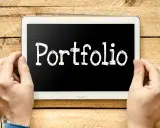Ręce trzymają tablet z napisem "Portfolio". Idealny do prezentacji prac podczas studiów.