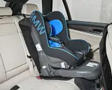 Fotelik dziecięcy BMW z systemem pasy isofix zamontowany na jasnej, skórzanej kanapie samochodowej.