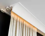 Nowoczesna blenda przy suficie ukrywa szynę zasłonową, tworząc elegancką linię.