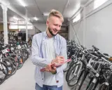Uśmiechnięty sprzedawca notuje w zeszycie, otoczony rzędami rowerów amerykańskich marek.