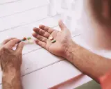 Mano che prende pillole da un portapillole. Speranza di guarigione con pembrolizumab.