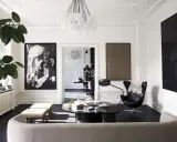 Ett elegant vardagsrum för ett hemma hos reportage. En stor porträttbild, en svart fåtölj och en rund soffa skapar en lyxig atmosfär.