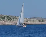 Segelboot gleitet durch das tiefblaue Wasser der kroatischen Kvarner Bucht, vorbei an felsigen, grünen Inseln.
