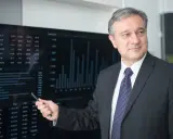 Mężczyzna w garniturze wskazuje na ekran z danymi finansowymi, wyjaśniając, kto płaci doradcy kredytowemu.