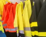 Variedad de ropa de alta visibilidad normativa en colores amarillo, naranja y negro, con bandas reflectantes para garantizar la seguridad en entornos de trabajo.