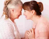 Un abbraccio tra madre e figlia, un momento di affetto che può aiutare a gestire i sintomas de alzheimer, con mani che si stringono.