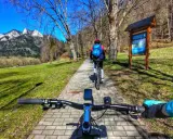 Rowerzyści przemierzają malowniczą ścieżkę rowerową w Szczawnicy, podziwiając górskie krajobrazy.