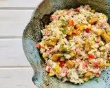 Pyszna sałatka z makaronem orzo i kurczakiem, z dodatkiem kukurydzy, papryki i ziół, podana w ceramicznej misie.