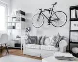 Nowoczesne przechowywanie rowerów na ścianie nad białą kanapą. Obok regały z pudełkami.
