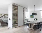 En vit rumsavdelare etta med hyllor delar av ett modernt vardagsrum och matplats.