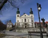 Kalwaria Zebrzydowska: Bazylika z wieżami i placem pielgrzymkowym, z ławkami i pomnikiem.