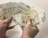 Dłonie trzymają wachlarz banknotów 200 zł. Zastanawiasz się, ile to brutto, jeśli 4200 netto to Twoja pensja?