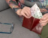 Emerytka wkłada pieniądze do portfela. Zastanawia się, ile wynosi deputat węglowy dla emerytów.