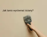 Ręka trzyma szpachelkę przy beżowej ścianie, szukając pomysłu na krzywe ściany.