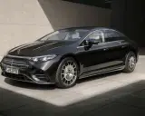 Schwarzer Mercedes-Benz EQS mit Facelift-Design, elegant vor Betonwand.
