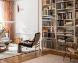 Acogedora sala de estar con una estantería repleta de libros, vinilos y objetos decorativos. La **decoración de librería** se integra perfectamente con el mobiliario moderno y la luz natural.