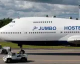En person sitter på taket av ett jumbo stay. Flygplanet är vitt med blå detaljer och texten "JUMBO HOSTEL" syns tydligt.