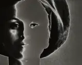 Volto femminile in profilo, un'icona di stile di Lillian Bassman, con un gioco di luci e ombre che ne esalta la misteriosa bellezza.
