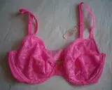 Reggiseno rosa acceso con pizzo floreale, spalline regolabili e un piccolo fiocco al centro. Taglia coppa DD.
