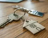Clés avec un porte-clés en forme de maison en bois, symbolisant l'accession à la propriété.