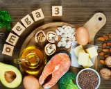 Assortiment d'aliments riches en oméga 3 : saumon, noix, avocat, œufs, huile, graines de lin, amandes, brocolis et beurre.
