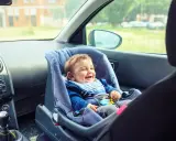Bebé feliz en silla de coche, asiento delantero, listo para la aventura.