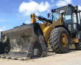 Żółta ładowarka stoi na placu budowy. Zastanawiasz się, ile zarabia operator koparki na godzinę?