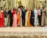 A diverse group poses in stylish dressy casual attire for a wedding, set against a backdrop of tall cacti.