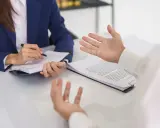 Rozmowa o zmianach w prawie pracy 2026. Kobieta w garniturze notuje, mężczyzna gestykuluje.