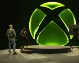 Osoby stoją przed wielkim zielonym logo Xbox. Czy to zapowiedź nowej gry, czy może Xsolla co to za platforma?