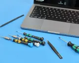 Narzędzia do naprawy iPhone'a: precyzyjne śrubokręty i pęseta obok laptopa. Przygotowanie do serwisu.