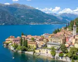 Färgstarka hus vid en azurblå sjö, omgivna av gröna berg. Ett perfekt exempel på mysiga resmål i Italien.