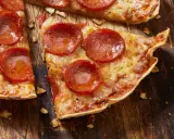 Pyszna pizza na tortilli z pepperoni, roztopionym serem i chrupiącym spodem, podana na drewnianej desce.