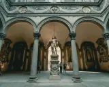 Cour intérieure de Florence avec une statue antique au centre. Une femme prend une photo de la statue florence.