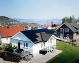 Vackra hus med solpaneler på taken, en del av ett system med Growatt 8000TL3-XH, i ett soligt bostadsområde med utsikt över en sjö.