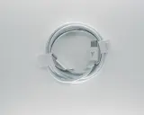 Biały kabel usb typu c, zwinięty w okrąg, z metalowymi końcówkami i logo producenta.
