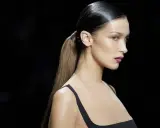 Bella Hadid luce un elegante peinado de cola de caballo con pelo efecto mojado, resaltando su perfil y maquillaje.