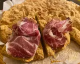 La ciaccia di Pasqua toscana, fragrante e dorata, è guarnita con fette di salume rosa.