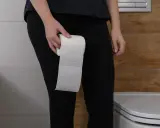 Osoba trzymająca rolkę papieru toaletowego w łazience, sugerująca problem z nykturią.