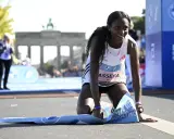 Glückliche Ruth Chepngetich kniet am Ziel des Berlin Marathons, die Ziellinie überquert.